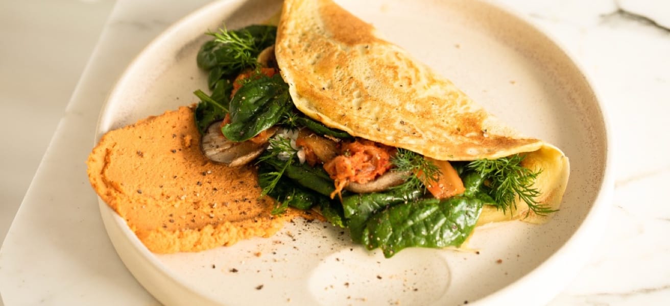 Photo of an omelette with greens on a white plate